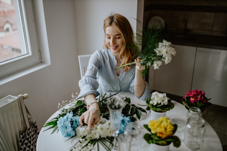 A woman arranging some flowers for a DIY craft at home.