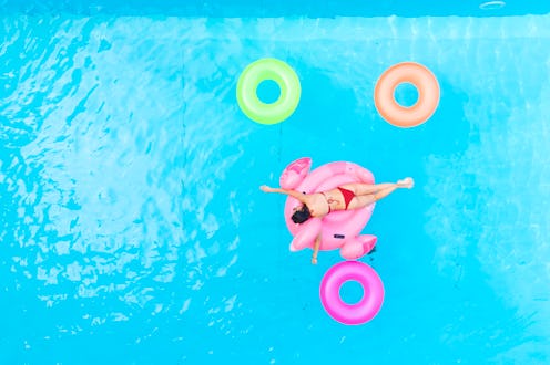 A woman swims on a flamingo pool float. Taking time off in a pandemic has benefits for burnout, expe...