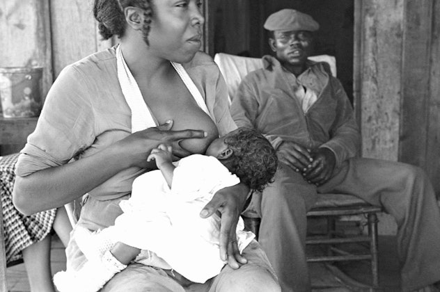 black and white photo of woman breastfeeding her child in a sharecropper community in Pulaski County...