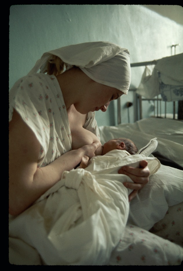 1975 color photo of woman breastfeeding newborn at hospital after birth