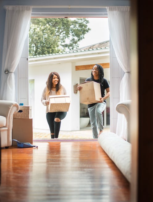 Two people carry boxes into a new house. If you're planning to move during the covid pandemic, docto...