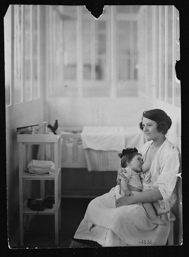 woman nursing baby in hospital nursery in 1930s