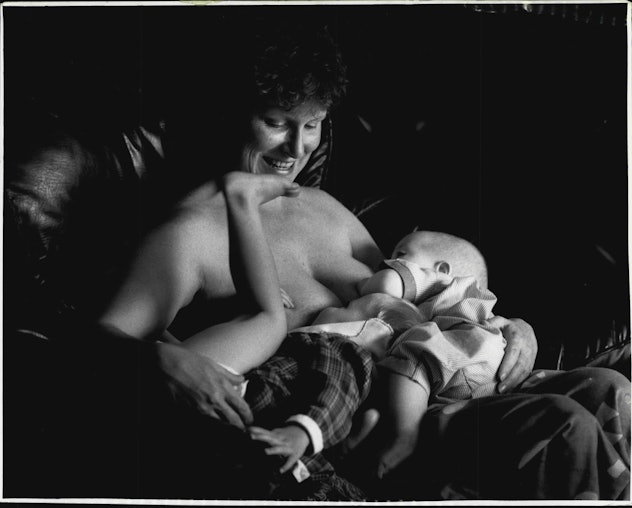 black and white photo of woman breastfeeding two children