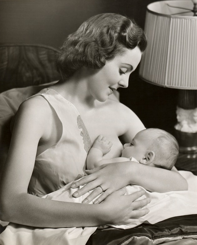vintage breastfeeding photo of woman breastfeeding baby propped on pillows