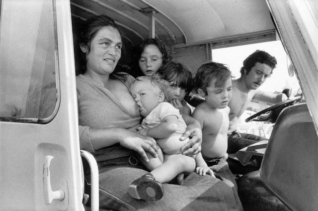 family traveling inside a van with four children in 1980s, mom in passenger seat nursing baby