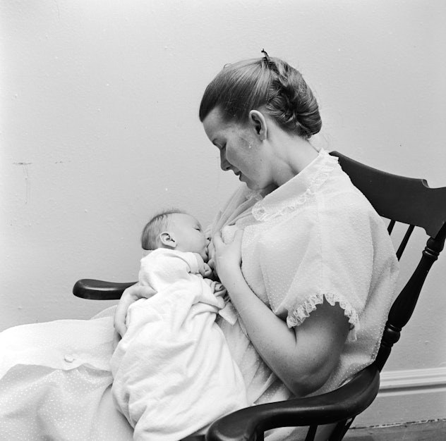 vintage photo of woman breastfeeding child in rocking chair in 1950s