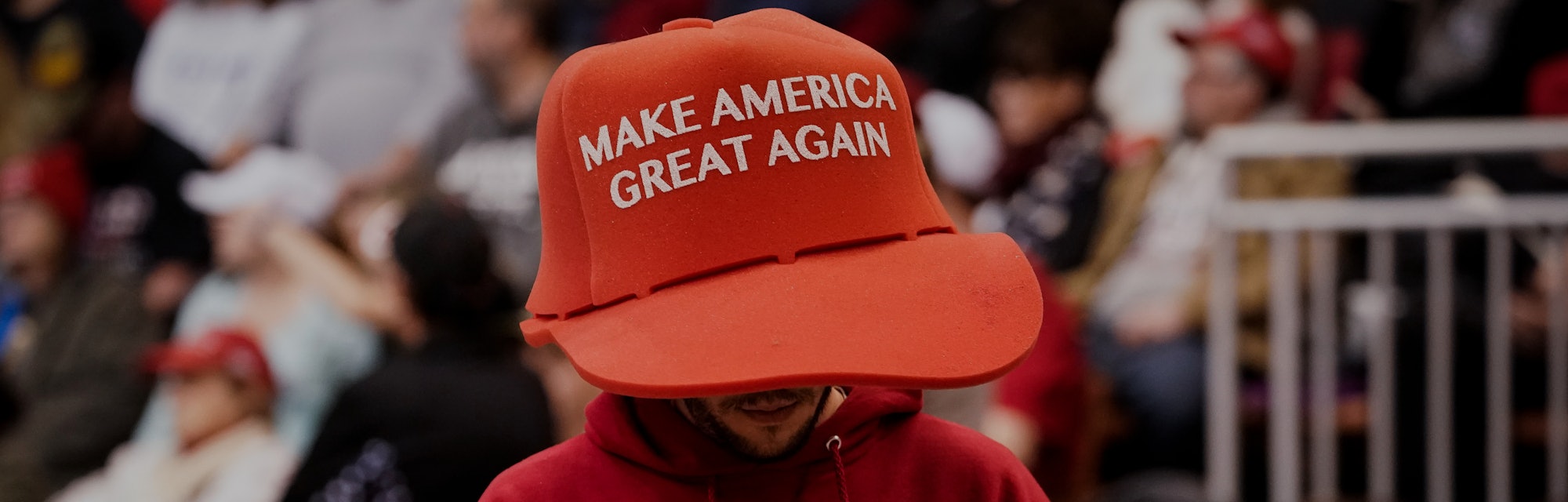 A Trump supporter can be seen wearing a large sized hat with "Make America Great Again" on it. His s...