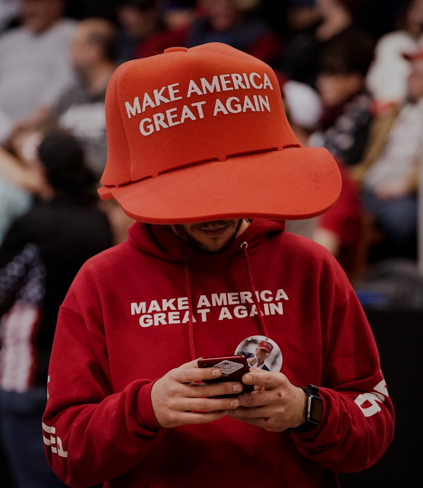 A Trump supporter can be seen wearing a large sized hat with "Make America Great Again" on it. His s...