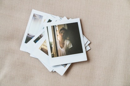 A stack of Polaroid pictures shows a girl standing in a sunny window on top.