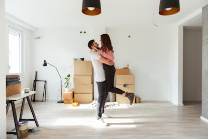 A young couple hugs in their new apartment after getting engaged and going through pictures.