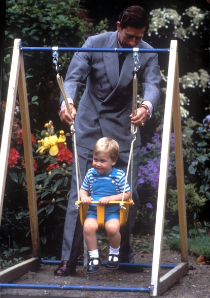Prince Charles swings Prince William on a swing set