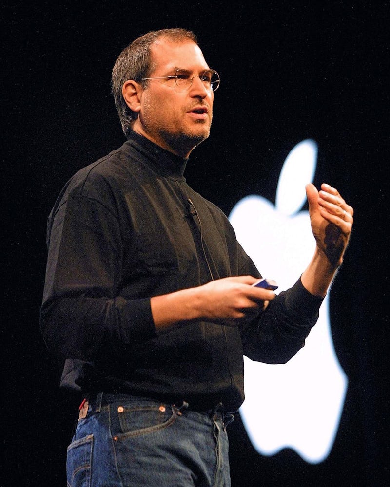 Steve Jobs in a black turtleneck, blue denim jeans and round glasses