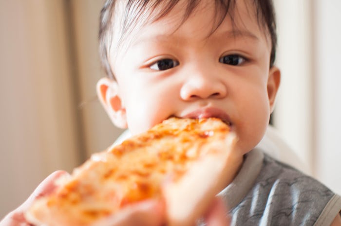 little baby boy eating slice of pizza