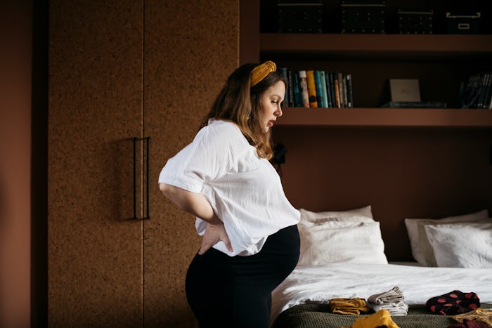 A pregnant woman standing in a bedroom thinking about protecting herself from Preeclampsia