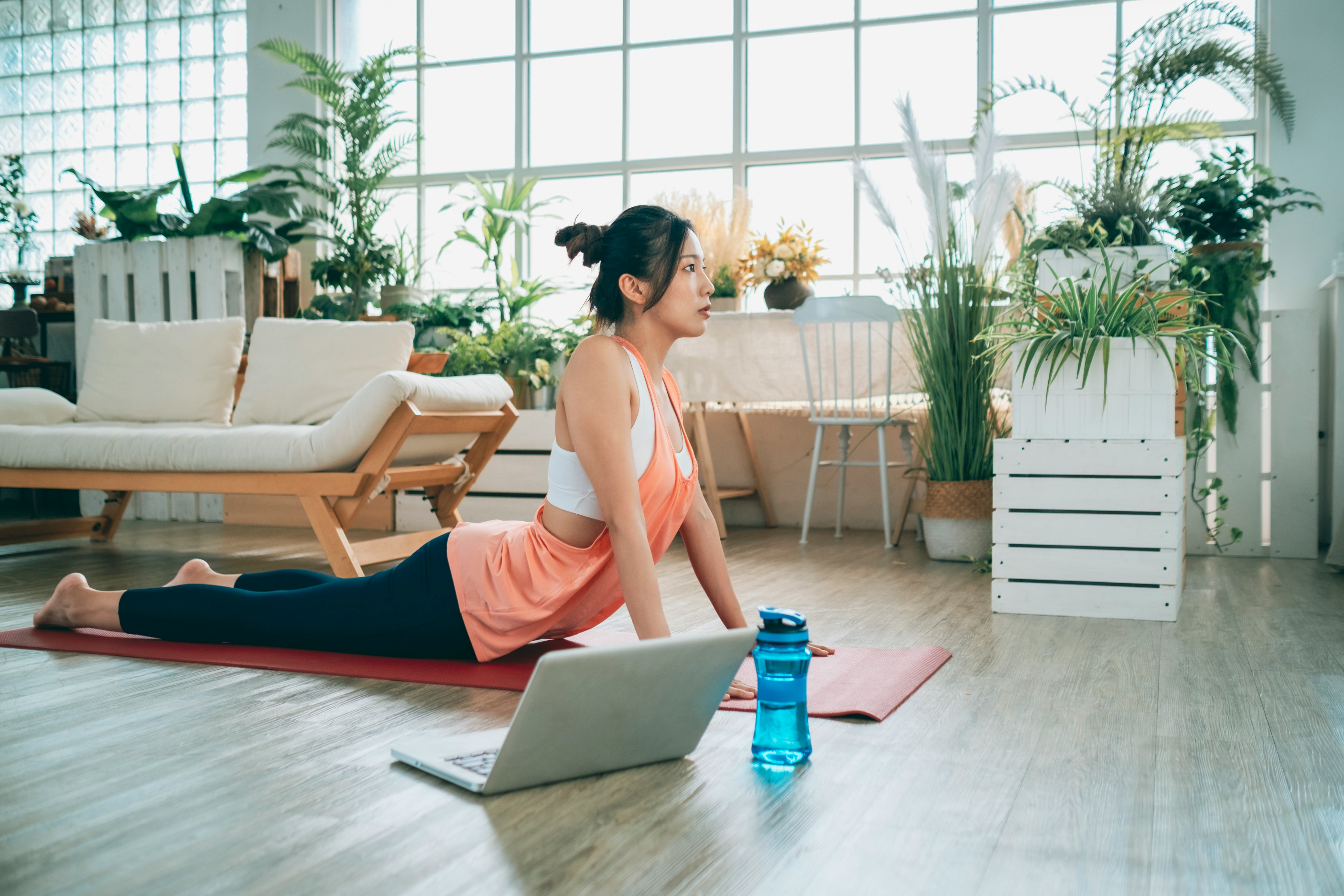 woman doing yoga in front of her laptop