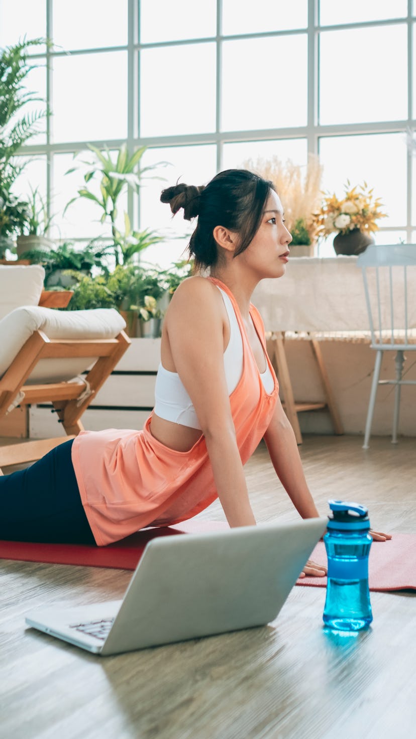 woman doing yoga in front of her laptop