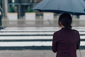 A woman holding an umbrella while standing in the rain in front of a clinic.