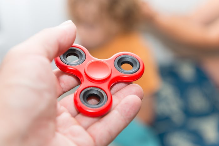 A hand holding a red fidget spinner