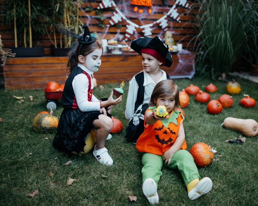 kids in halloween costumes sitting in backyard