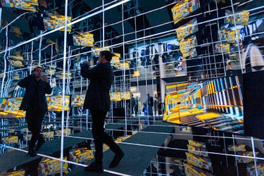 A man standing in a mirrored room of TVs.