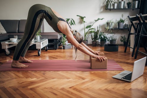 A person holds a plank on her yoga mat at home. Knowing how to modify yoga poses for your own body c...