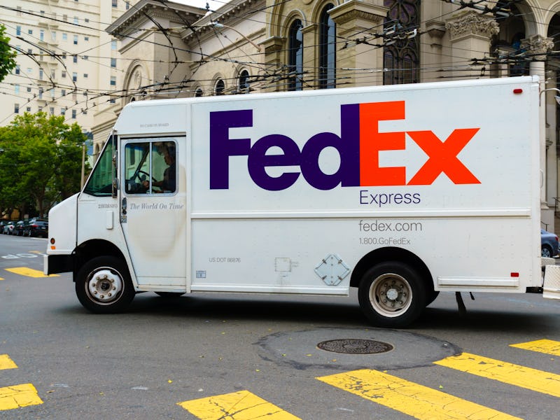 A FedEx truck with the purple and orange logo is seen on a road.