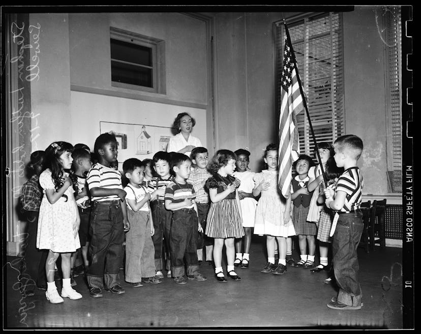 This vintage back to school photo shows a group of children reciting The Pledge Of Allegiance. 