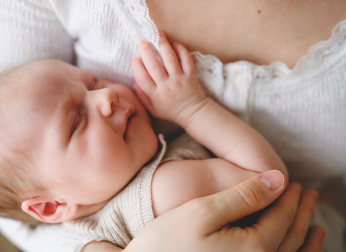 A woman holding her baby, with the baby leaning against the mom's postpartum boobs