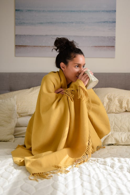 A woman in a yellow blanket drinks tea. Here's what happens to your body when you stop drinking alco...