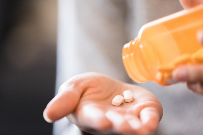 A closeup of a woman's hands taking fertility drugs from the bottle