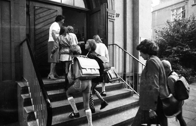 Kids are walking up to the school doors in this vintage back to school photo. 
