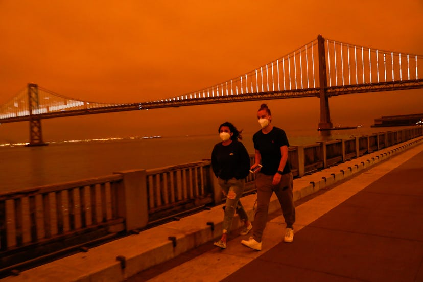 Two people walk in San Francisco through wildfire smoke. Smoke from wildfires can harm your health. 