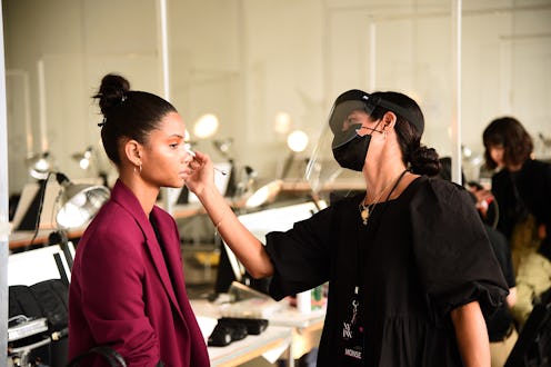 A makeup artist applying makeup to a model backstage during fashion week