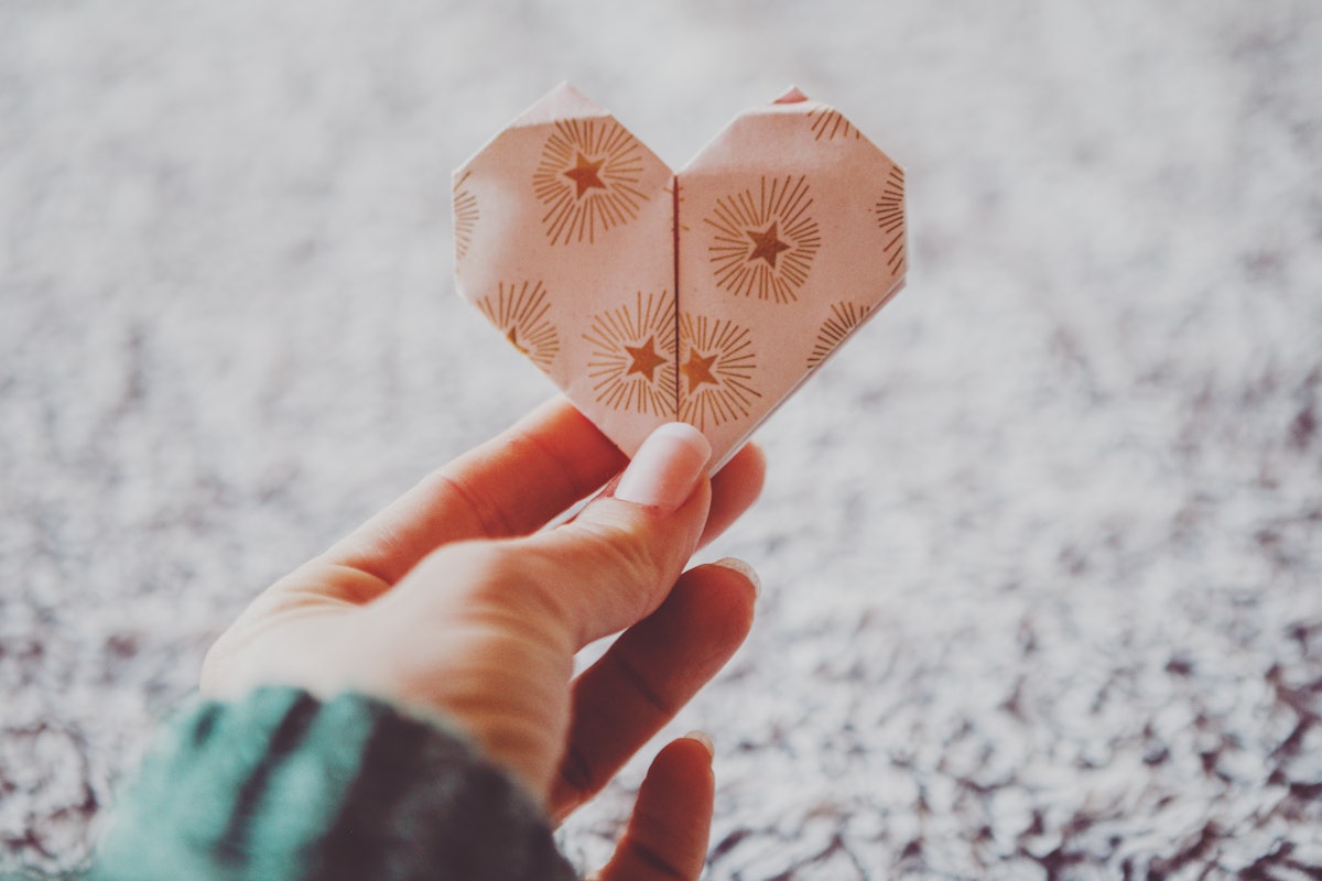 A woman holds up an origami heart, one fall pandemic hobby women swear by.