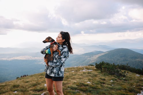 A woman hiking holds up a dog. Here's how getting a dog changes your brain