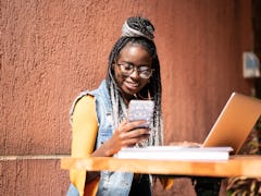 A happy woman wearing a denim vest and glasses texting her work BFFs via a clevver & funny group cha...