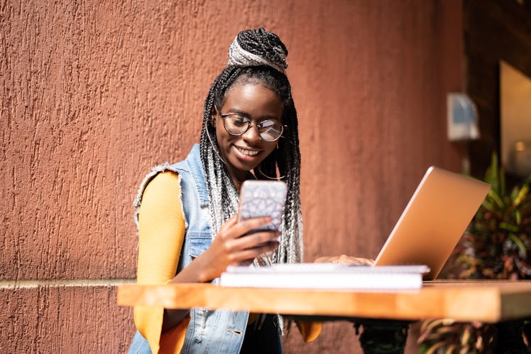 A happy woman wearing a denim vest and glasses texting her work BFFs via a clevver & funny group cha...