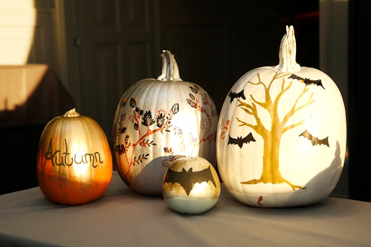 Painted pumpkins sit on a table while the sun shines on them.