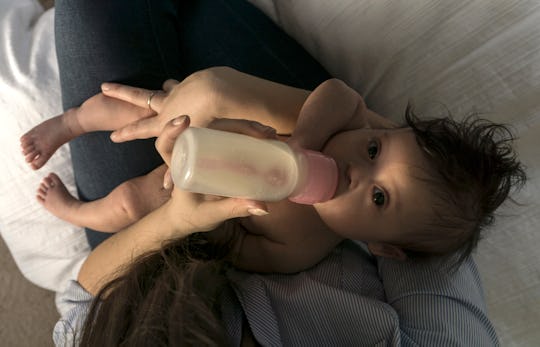 baby having a bottle on mom's lap