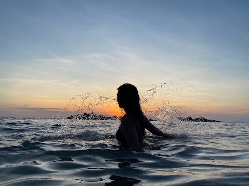 A woman splashes in the ocean at sunset. Experts reveal what happens to your brain when you stop dri...