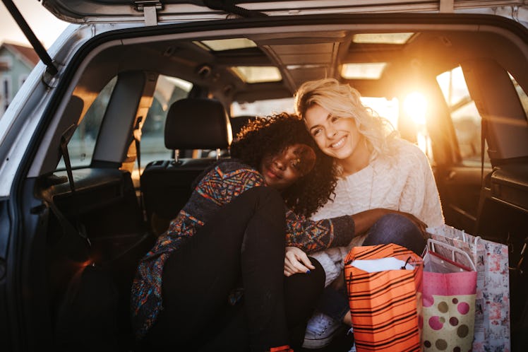 A young lesbian couple snuggles in the trunk of their car on a chilly fall day before trying some fa...