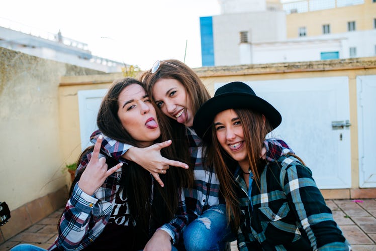Three friends hang out and have fun on the roof, while wearing matching flannel shirts. 