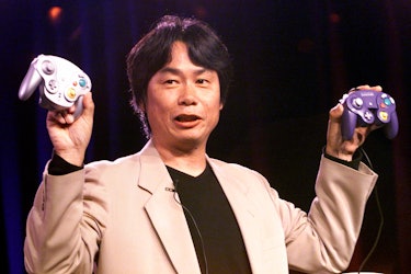 Miyamoto holding two GameCube controllers.