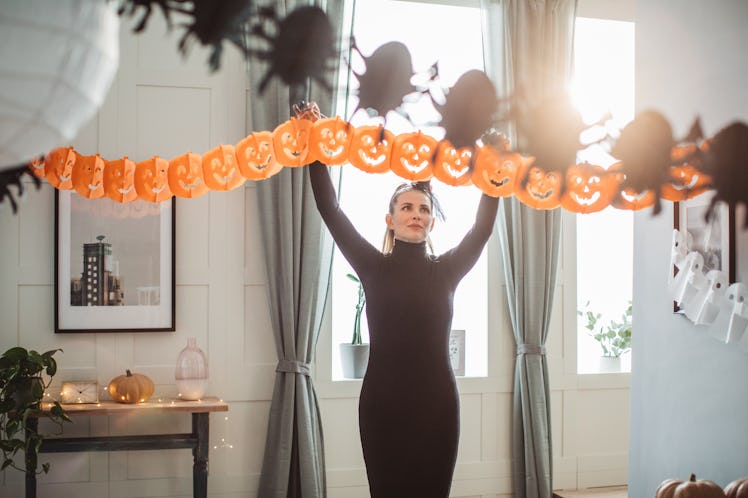 A woman hangs up a Halloween banner in her home.