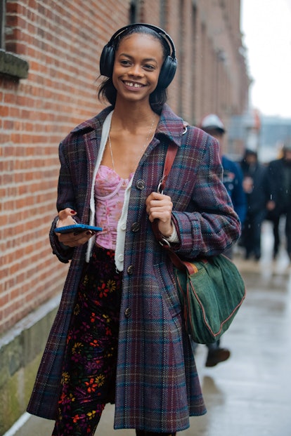 Floral corset worn with shrunken cardigan and plaid coat in street style.
