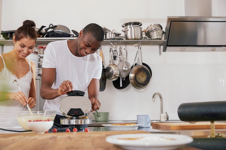 A happy couple makes waffles in their bright kitchen.