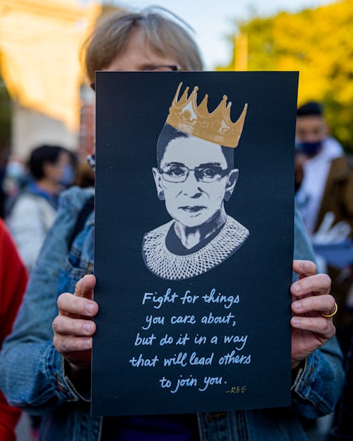 A woman holds up a sign with an image of Ruth Bader Ginsburg at a memorial. Experts explain why fear...