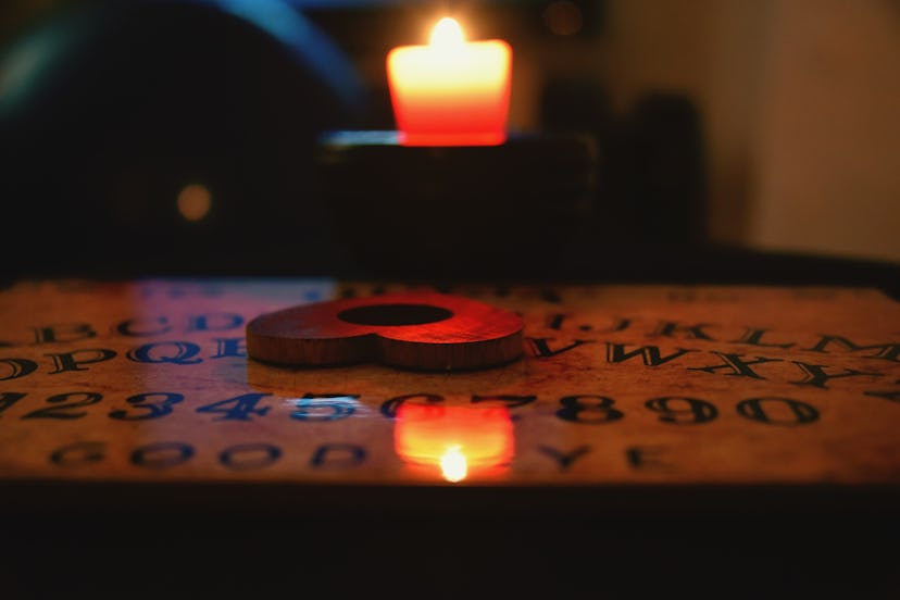 Ouija board set up in front of a candle.