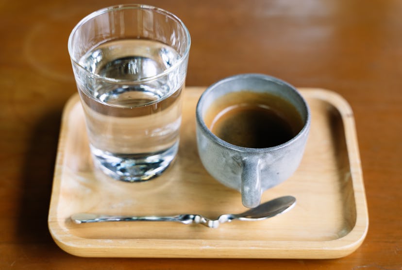 A glass of water and cup of coffee on a light wood tray. What happens to your brain when you stop dr...