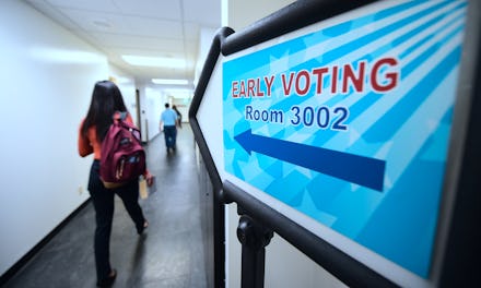 A woman entering the an election room with a large blue arrow sign